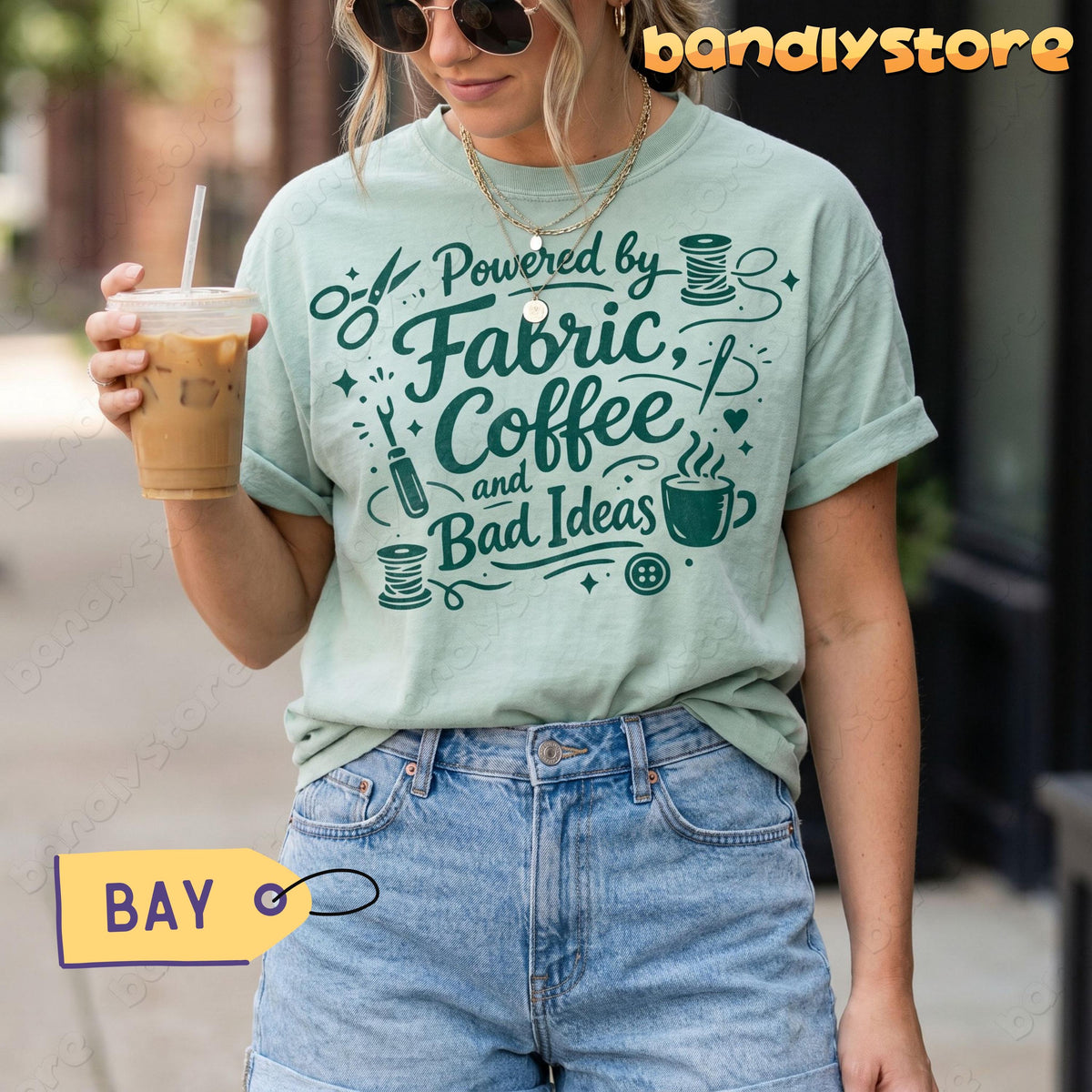 Linocut Sewing T-Shirt in Bay on a woman holding iced coffee outdoors, front view.