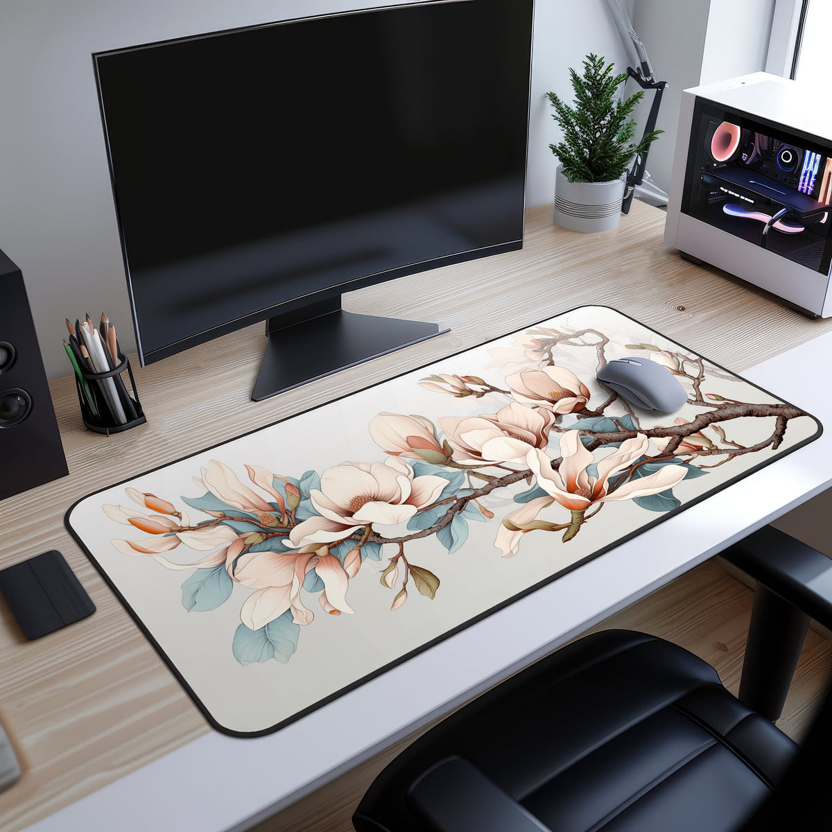Magnolia Flowers Desk Mat on a light wood desk before a black monitor with grey mouse, plant and white PC.