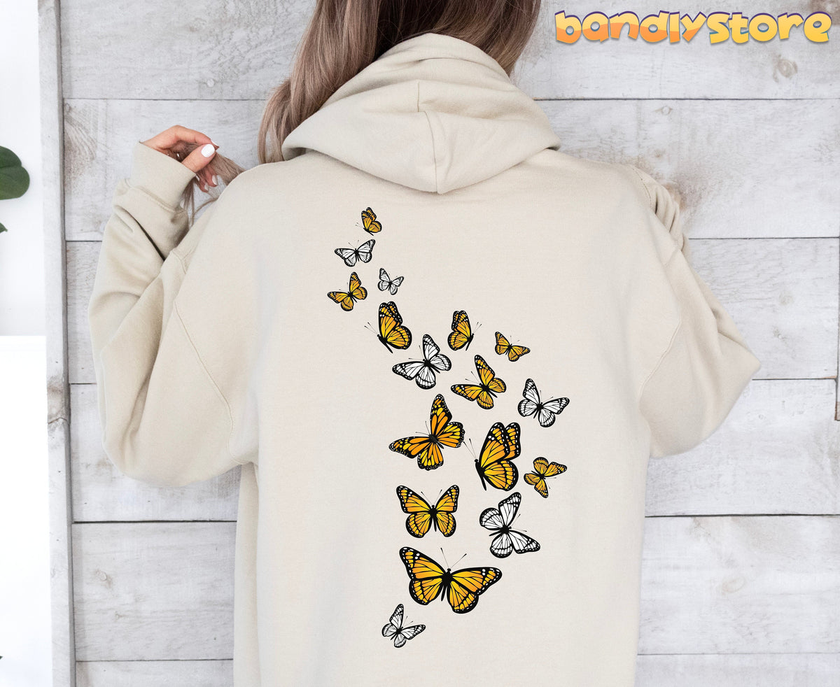 Monarch Butterfly Hoodie in sand, back view on a person against a white wooden wall.