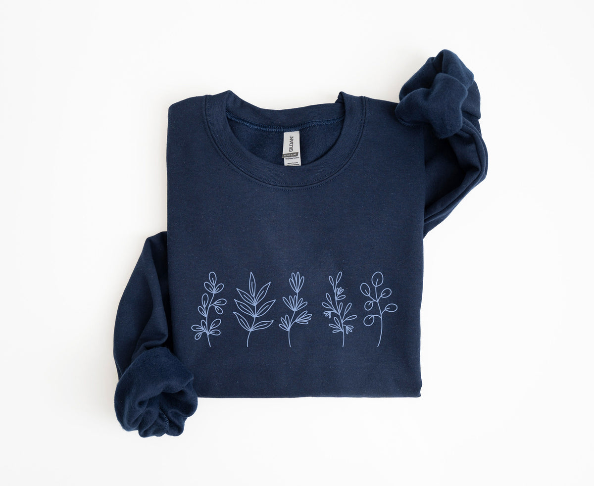 Monochrome Floral Sweatshirt navy crewneck folded flat on white, light blue line-art botanicals across the chest.
