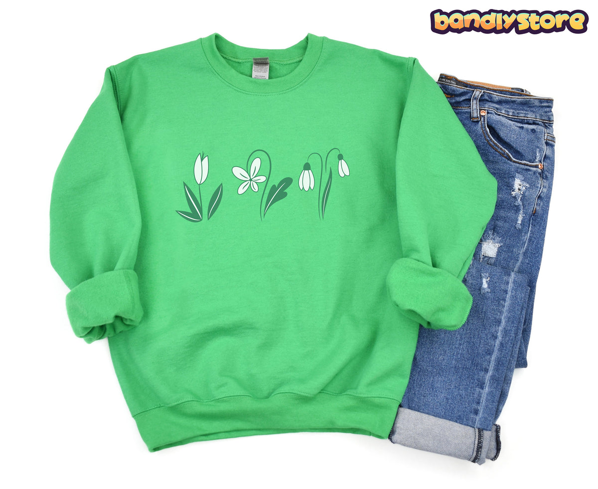 Monochrome Spring Flowers Sweatshirt in Irish Green, flat-laid front view beside folded distressed blue jeans.
