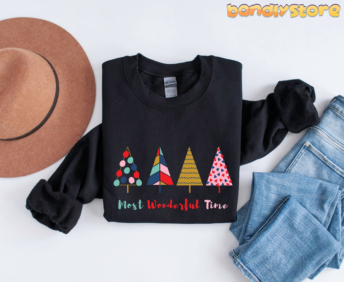 Most Wonderful Time Christmas Trees Sweatshirt in black laid flat beside a brown hat and blue jeans.