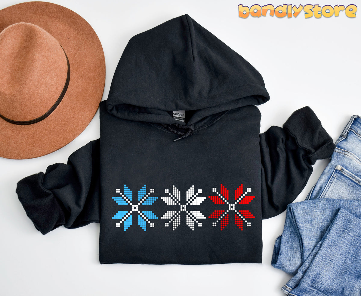 Old Fashioned Snowflake Hoodie in black laid flat beside a brown hat and blue jeans on white.