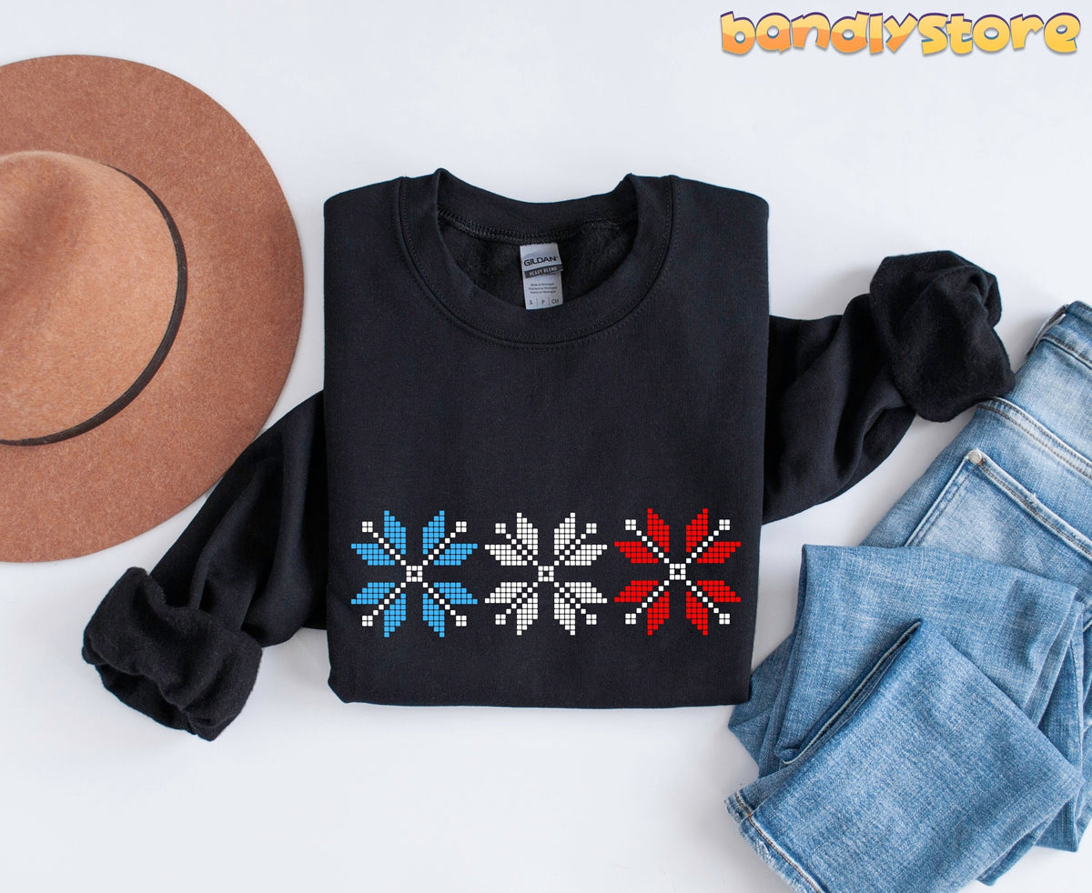 Old Fashioned Snowflake Sweatshirt in black folded flat beside a hat and jeans on a white background.
