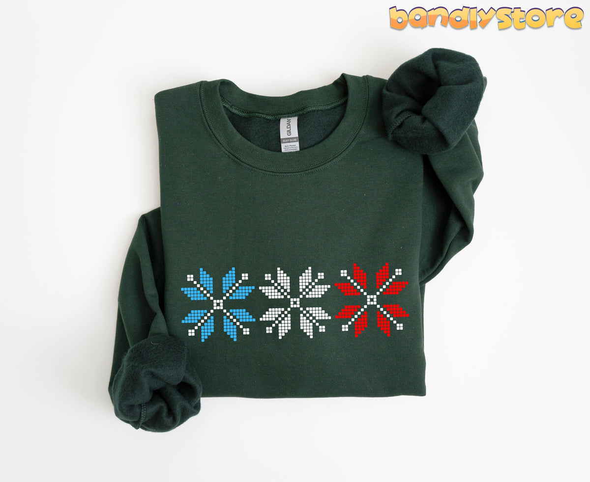 Old Fashioned Snowflake Sweatshirt in forest green, folded flat on white with blue, white and red pixel snowflakes.