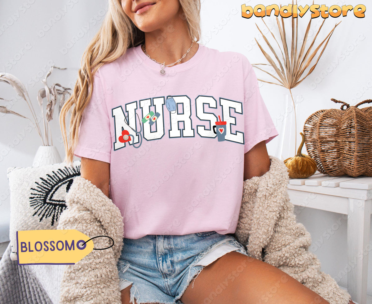 Personalized Nurse T-Shirt in Blossom on a seated woman beside dried plants and woven pumpkins.