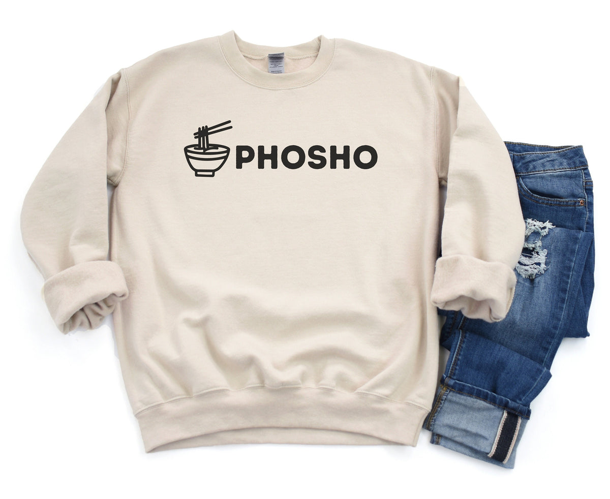 Pho Sho Sweatshirt in sand, flat lay front view with noodle bowl graphic beside folded ripped blue jeans.