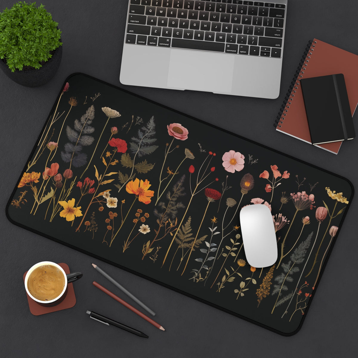 Pressed Wildflowers Desk Mat 12 ร 22 inches top-down on a desk with laptop, plant, coffee, pencils, notebooks and mouse.