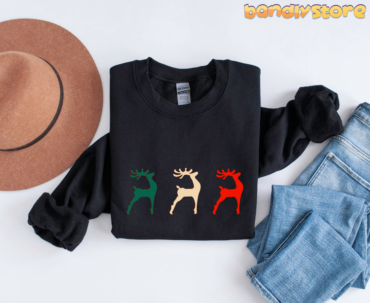 Reindeer Christmas Sweatshirt black folded flat beside a hat and jeans on white.