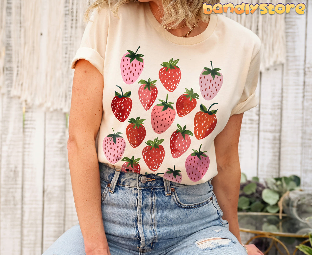 Retro Strawberry T-Shirt in natural on a seated person against white wood wall with macrame and plants.