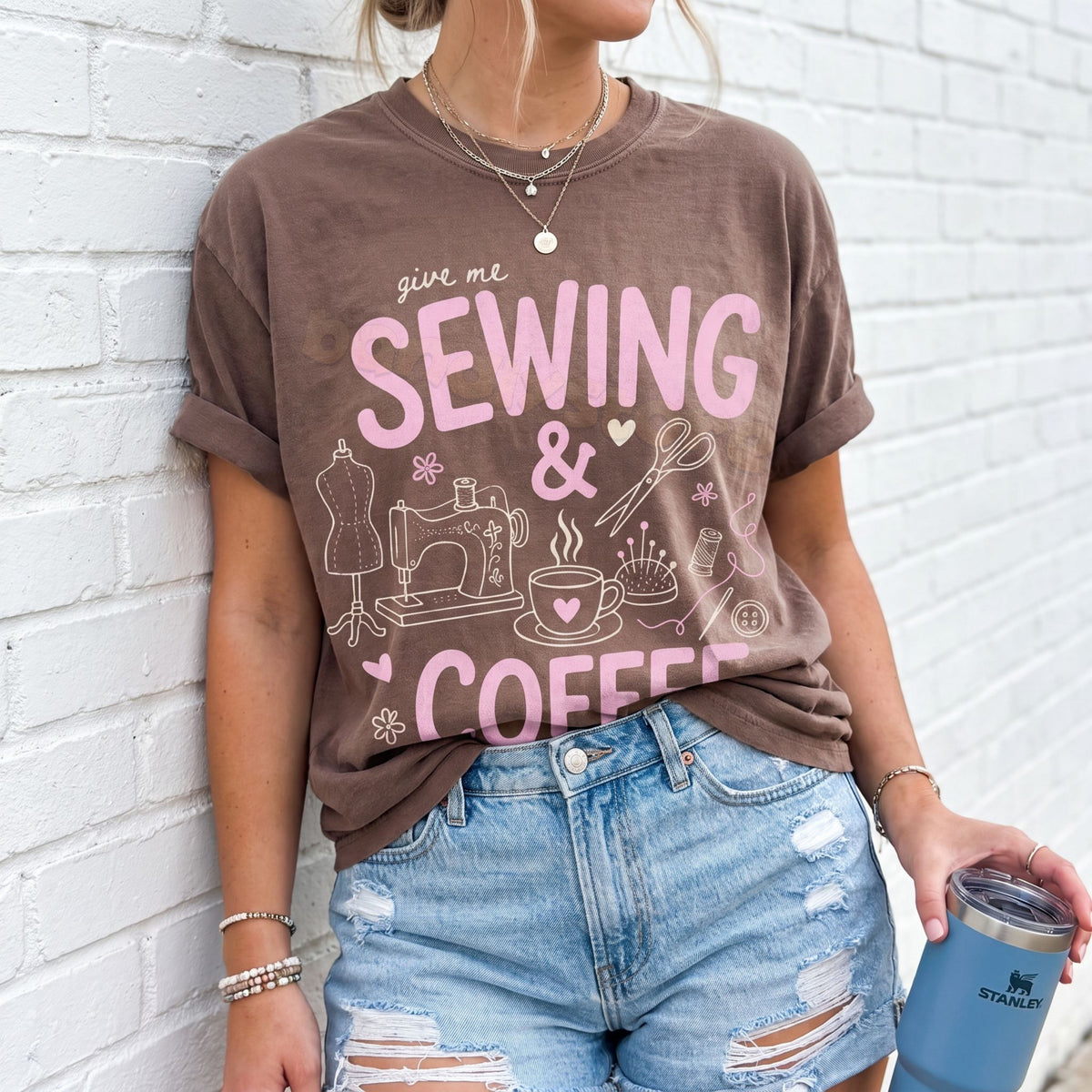 Sewing And Coffee T-Shirt in Espresso worn by person leaning on white brick wall holding tumbler