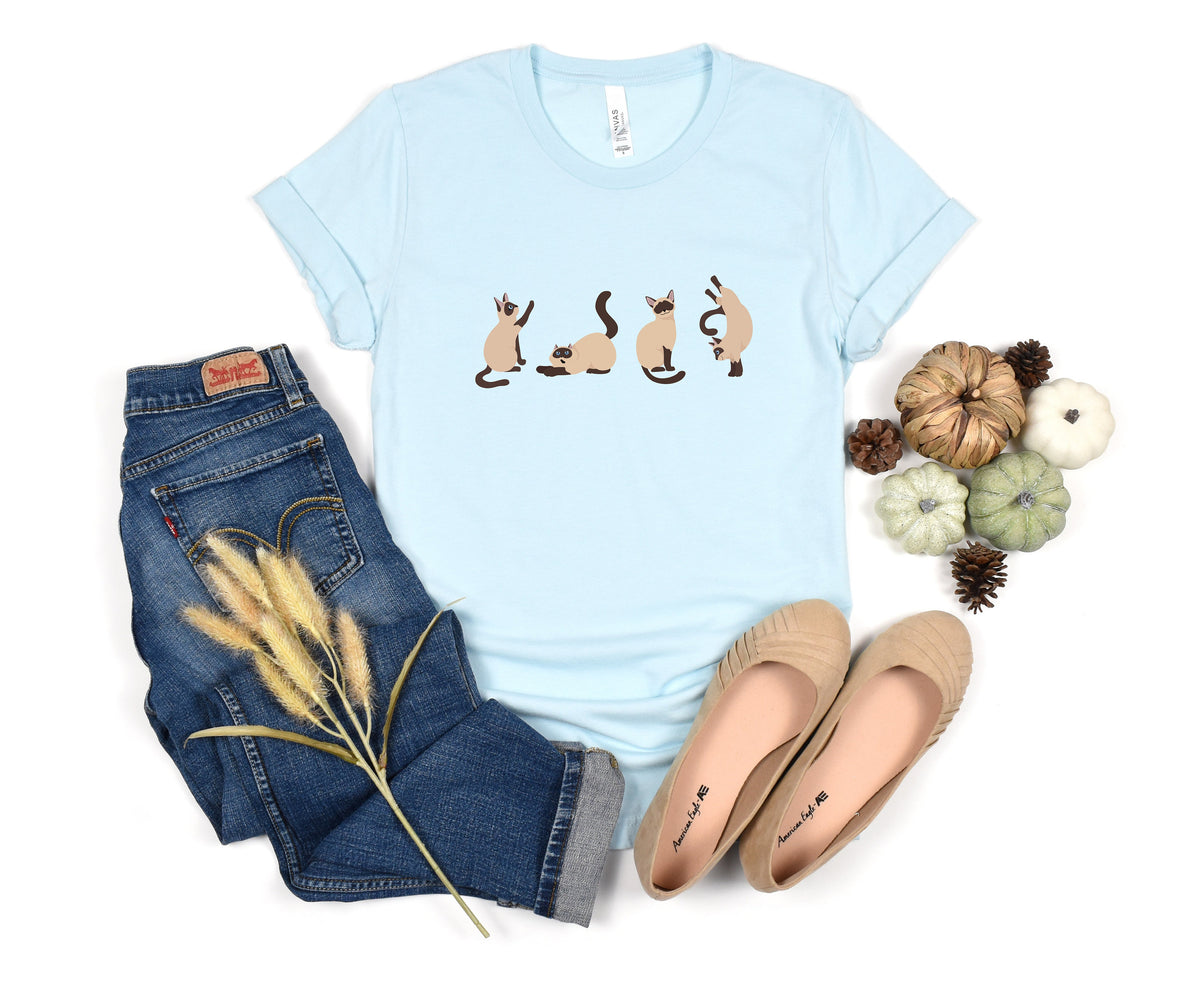 Siamese Cat T-Shirt in light blue laid flat beside jeans, shoes, pumpkins and pinecones.