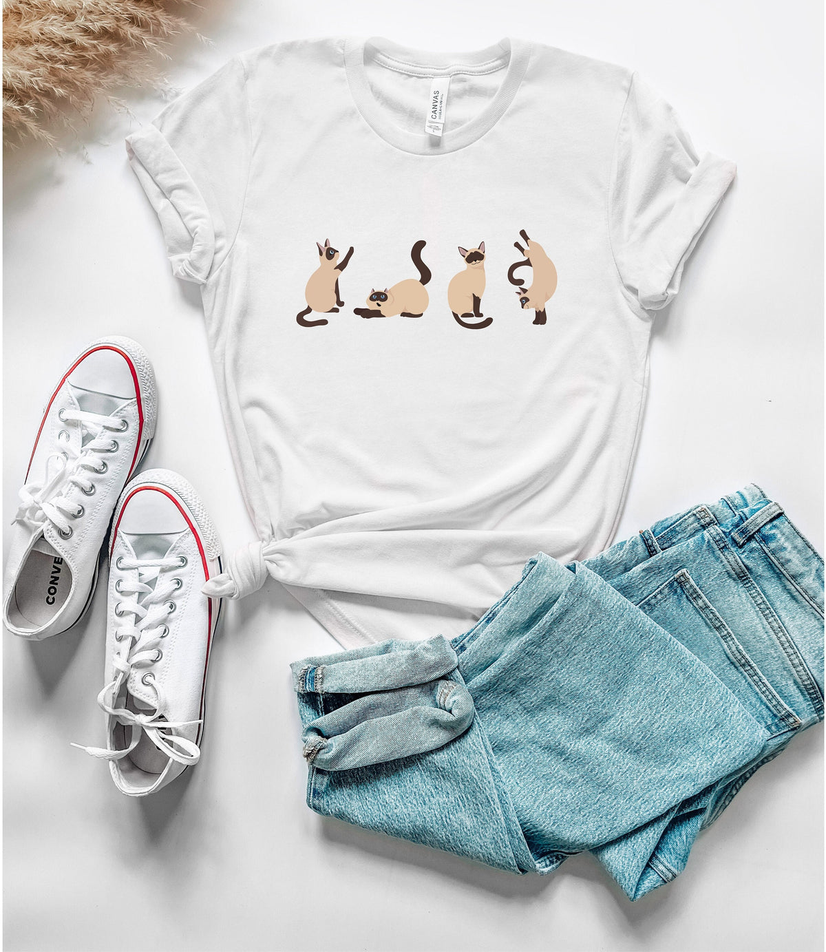 Siamese Cat T-Shirt white flat-laid from above next to sneakers, blue jeans and pampas grass.