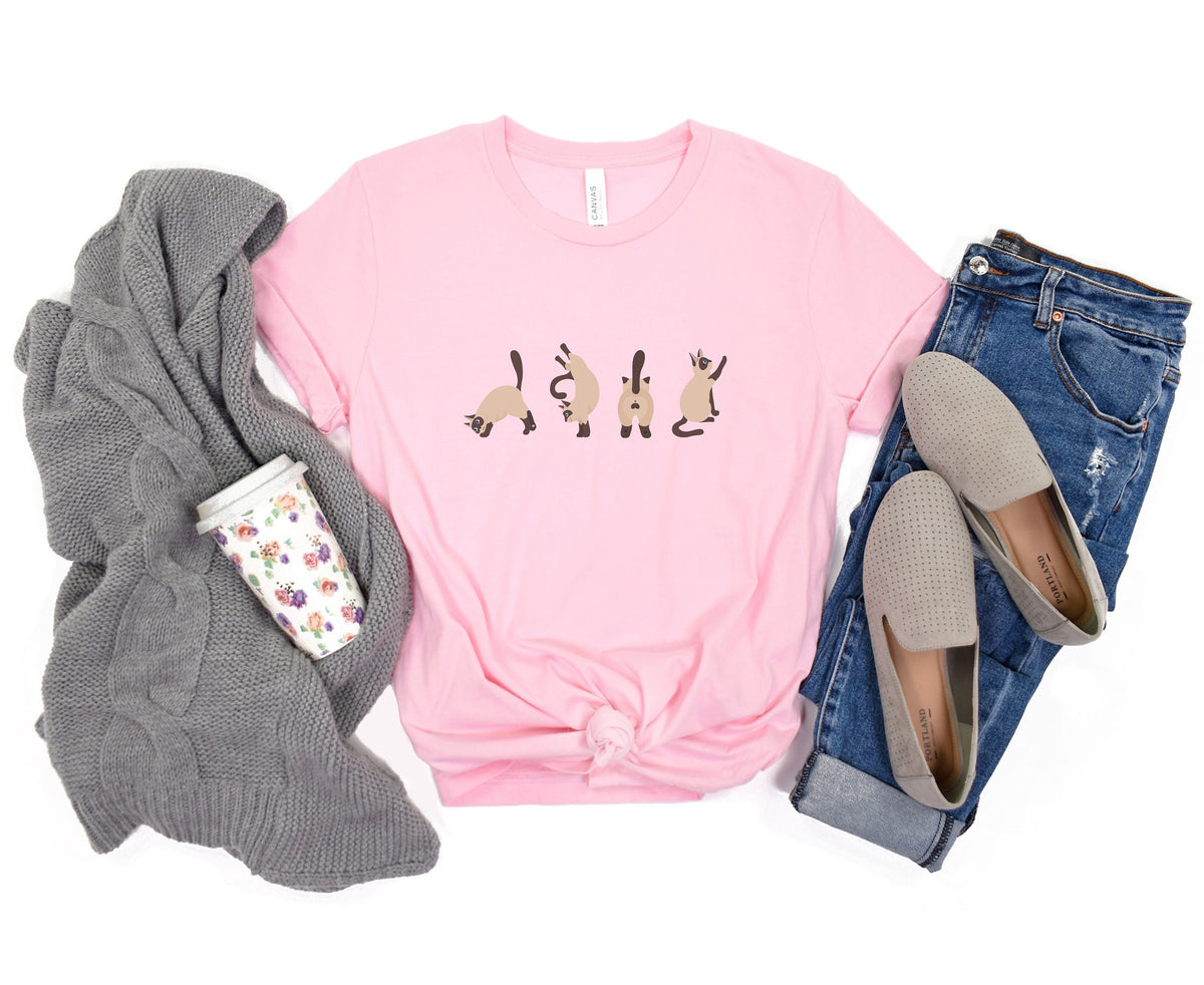 Siamese Cat T-Shirt in pink laid flat with grey sweater, floral mug, jeans and loafers around it.