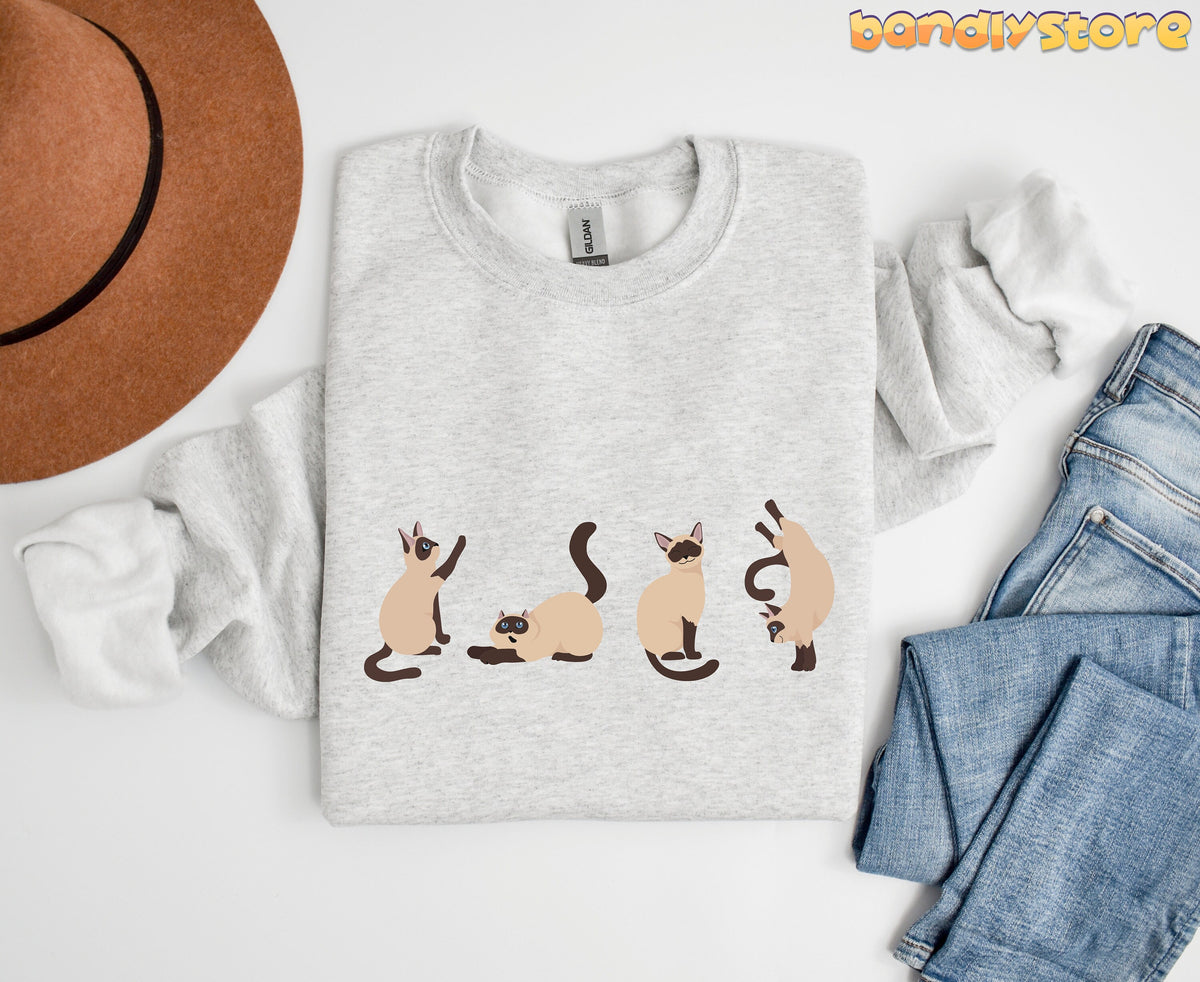 Siamese Cat Sweatshirt in ash flat-laid from above beside a brown hat and blue jeans.
