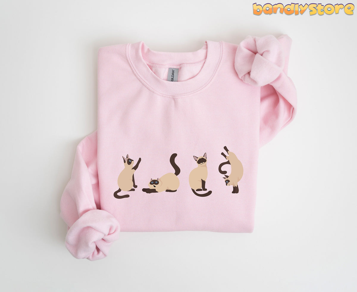Siamese Cat Sweatshirt light pink folded flat on white with four cartoon Siamese cats across the chest.