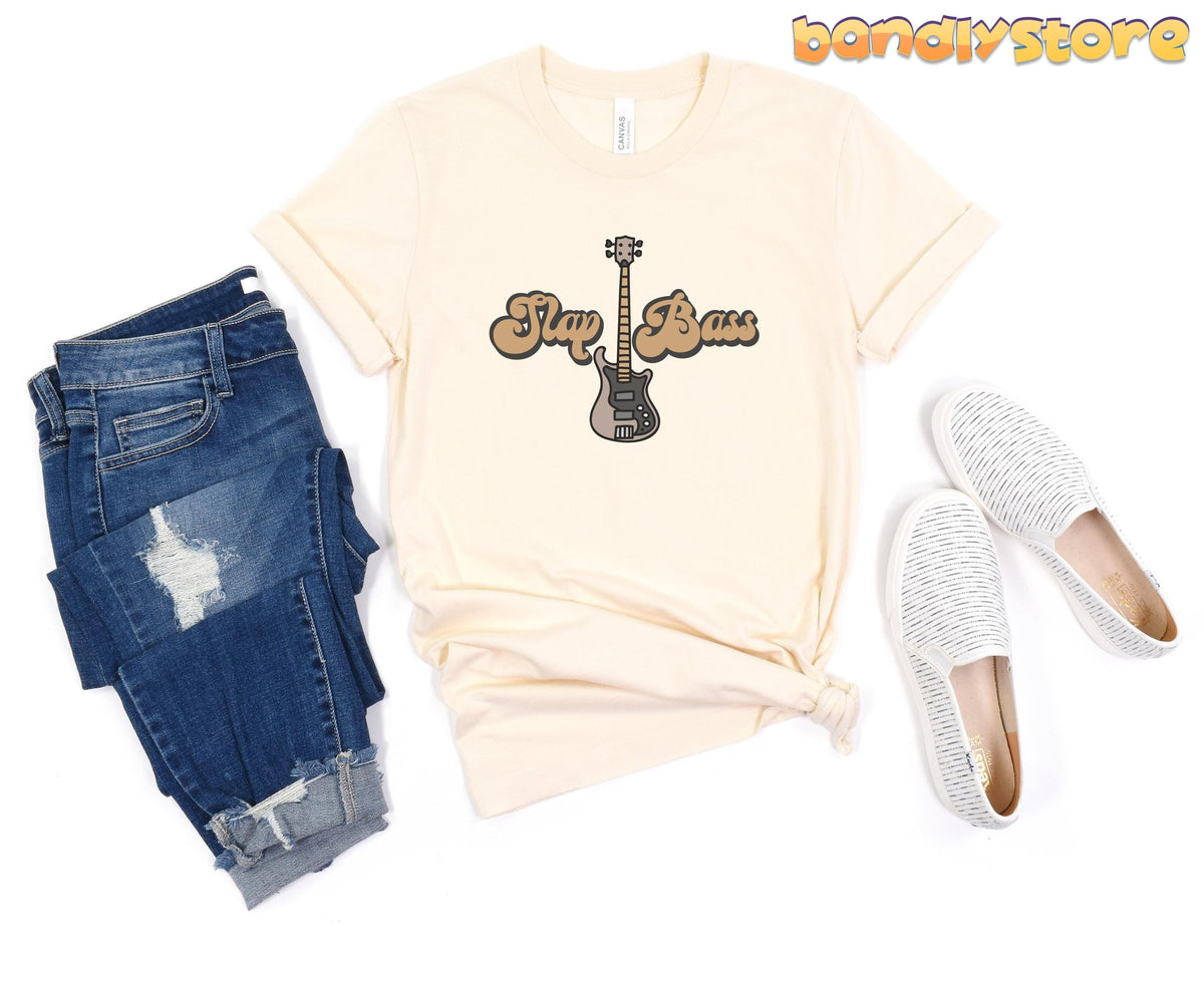 Slap Bass T-Shirt in natural laid flat from above beside ripped blue jeans and white slip-on shoes.