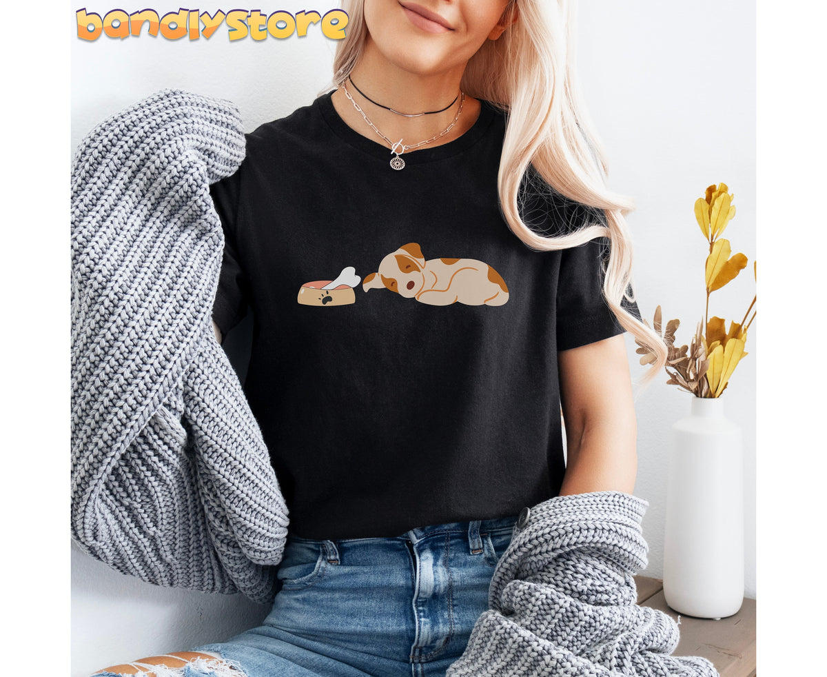Sleeping Dog T-Shirt in black on seated model holding knit sweater beside vase with dried plants.