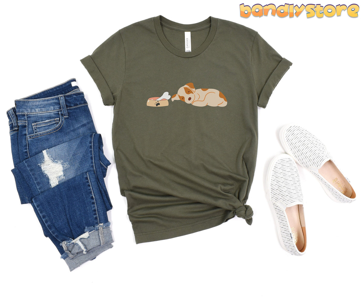 Sleeping Dog T-Shirt in military green laid flat beside ripped blue jeans and white slip-on shoes.