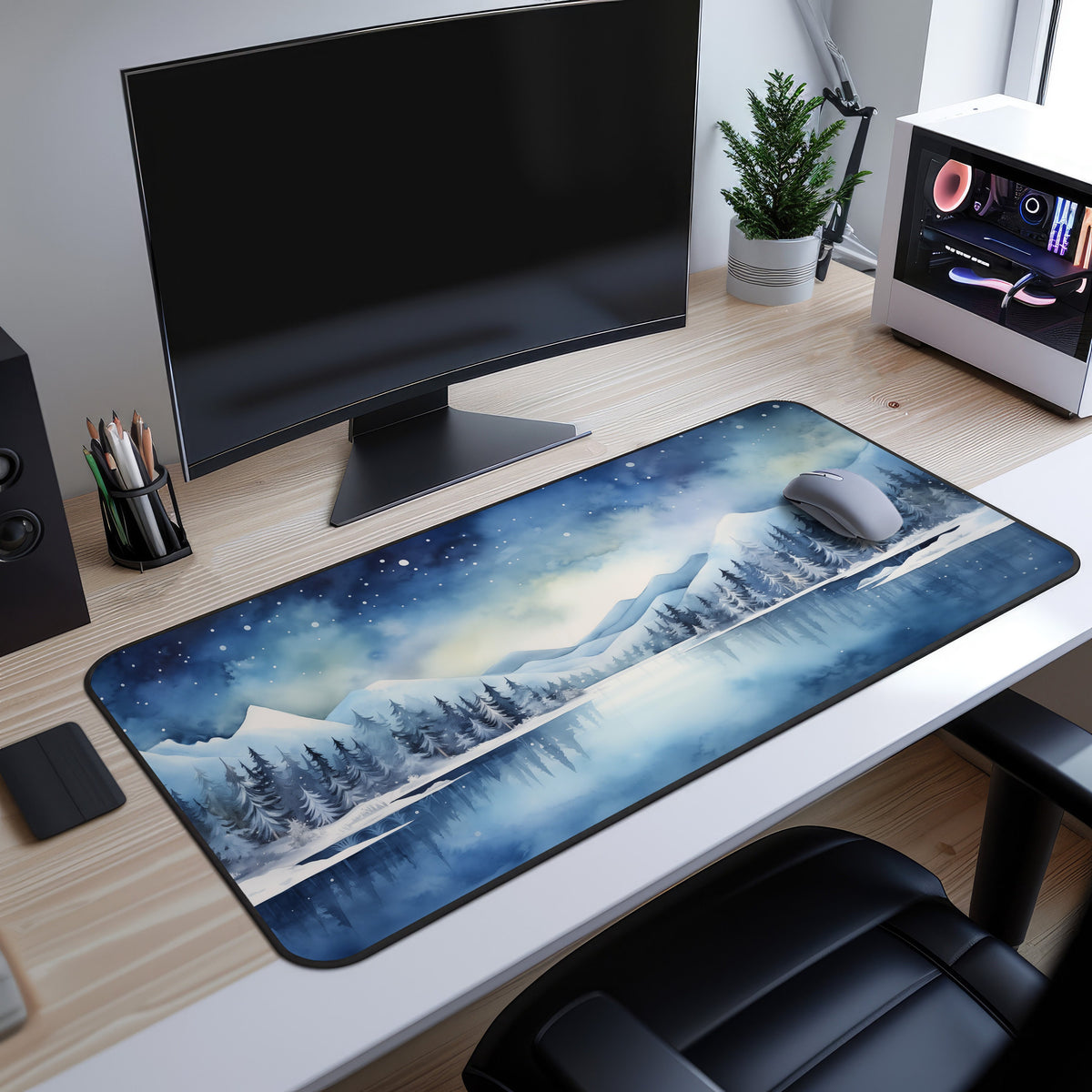 Snow Mountains Desk Mat on a wooden desk under a monitor beside a mouse, plant and white PC.