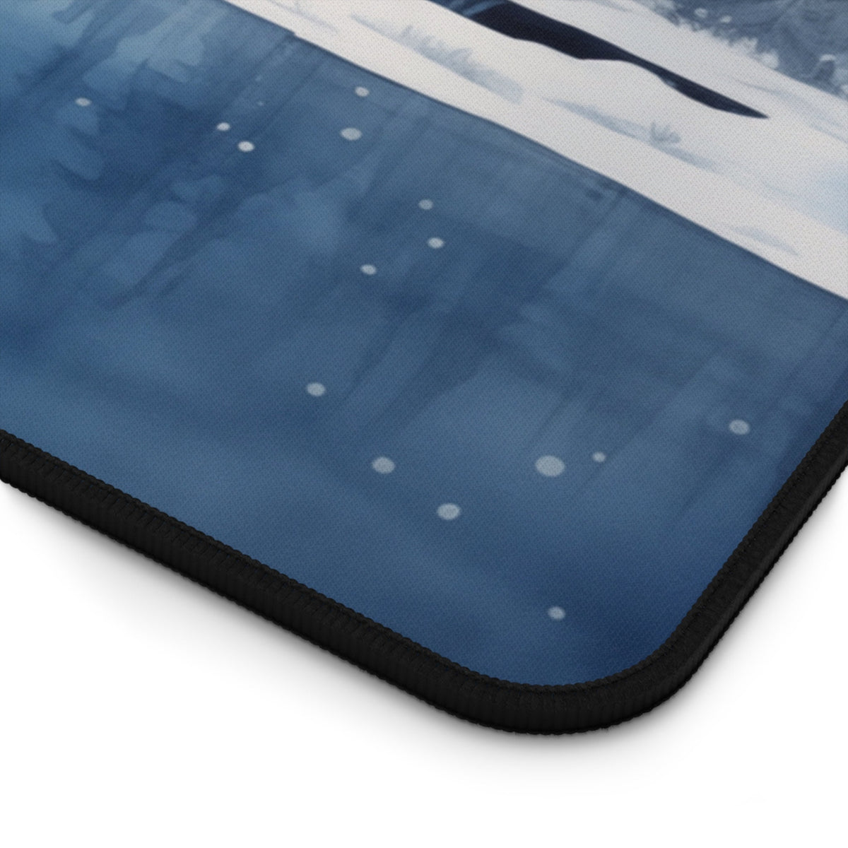 Snow Mountains Desk Mat corner close-up on white background showing blue print with white dots and black stitched edge.