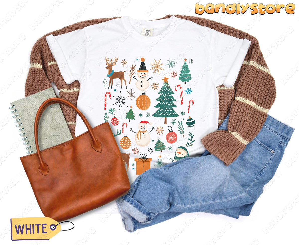 Tis The Season Christmas T-Shirt in white flat-laid with brown cardigan, tote, notebook and jeans.