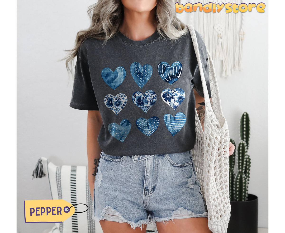 Toile De Jouy Hearts T-Shirt in pepper on a model standing indoors holding a white macrame bag beside a cactus.