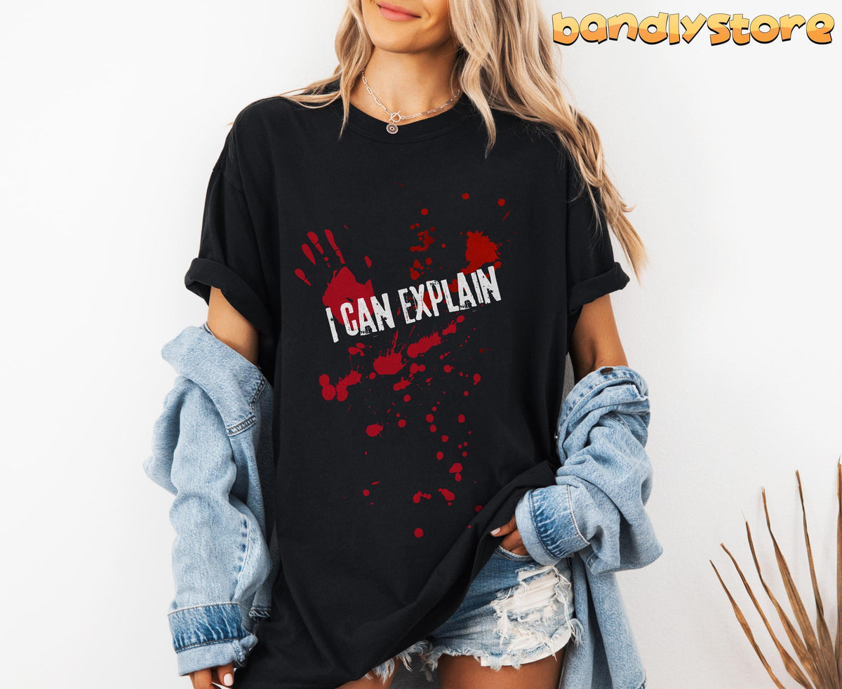 I Can Explain T-Shirt black tee with red handprint and blood-splatter text, worn front-facing with denim jacket and shorts.