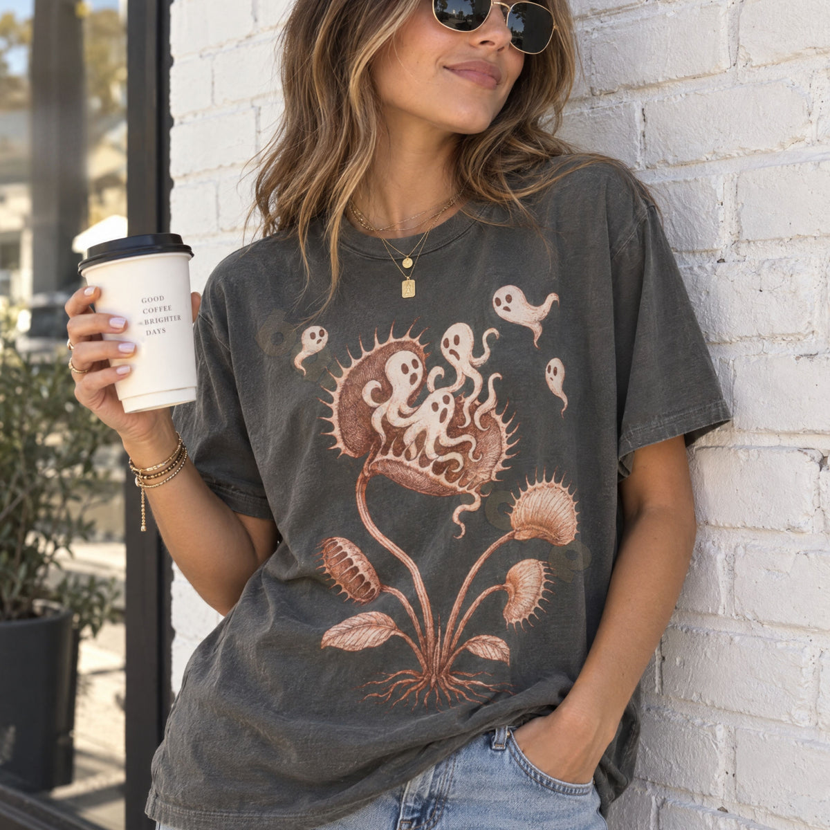 Vintage Ghost Eating Flytrap T-Shirt in pepper on woman holding coffee cup against white brick wall.
