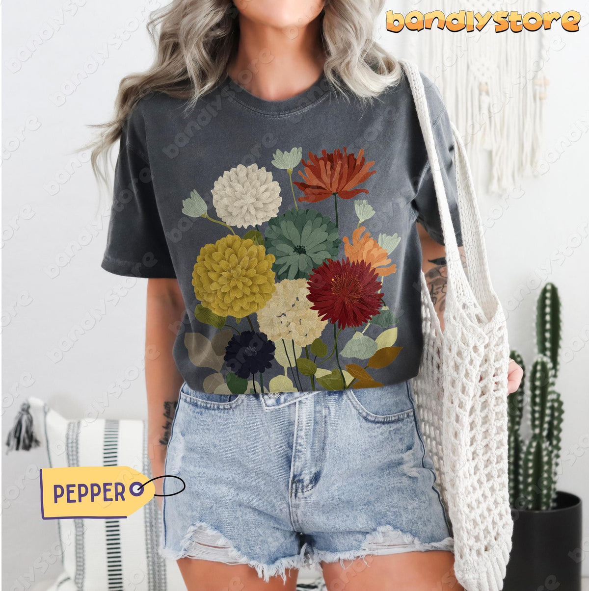 Vintage Earthy Wildflowers T-Shirt in Pepper on a model facing forward holding a woven bag by a cactus.