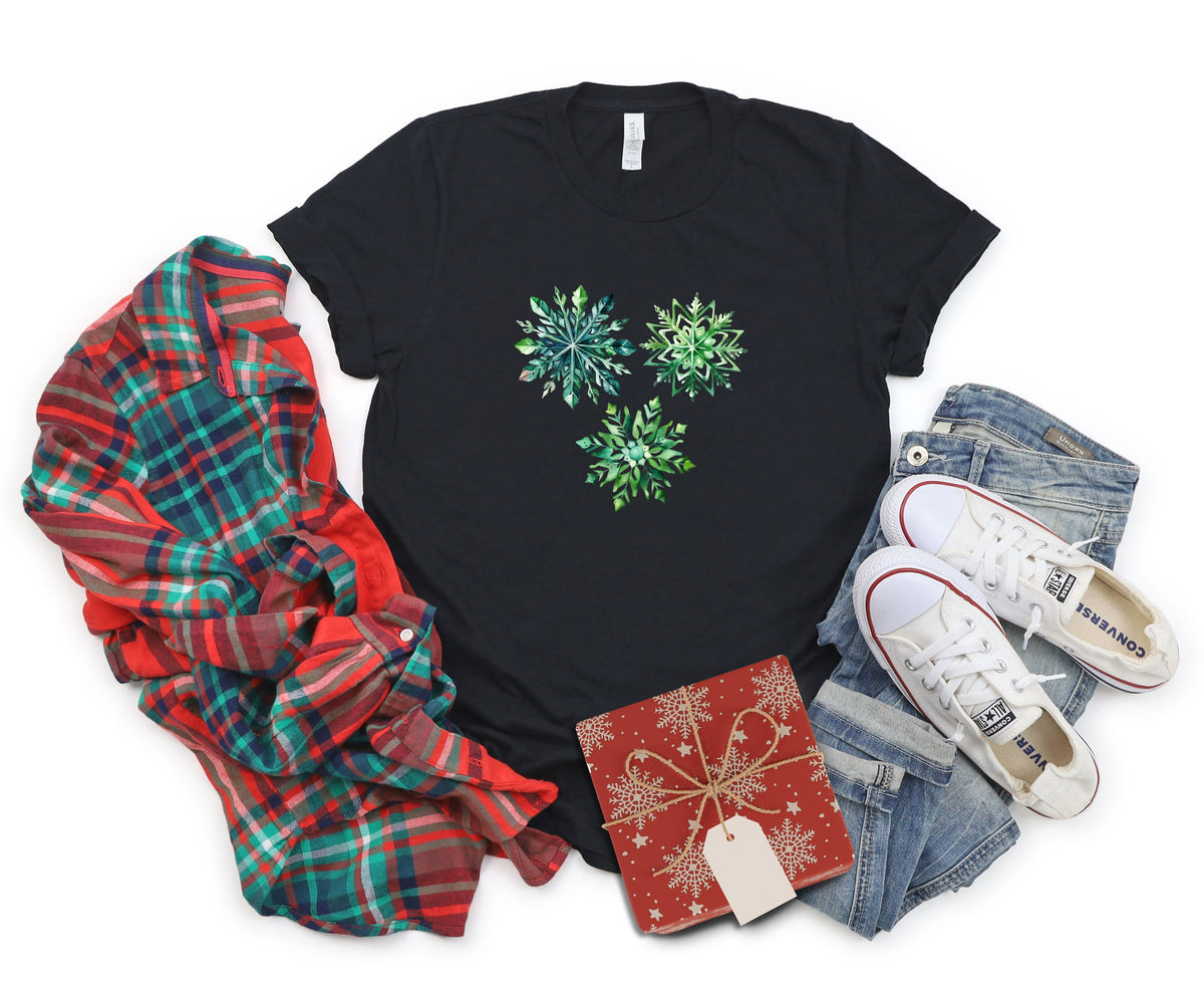 Watercolor Snowflakes T-Shirt in black flat-laid with plaid shirt, jeans, sneakers and gift box.