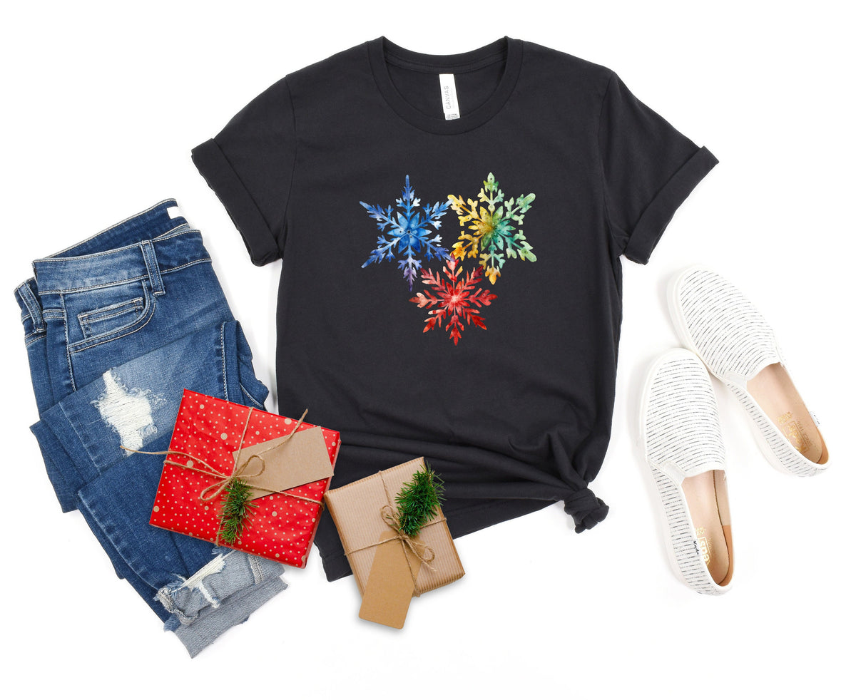 Colorful Watercolor Snowflakes T-Shirt in dark grey flat-laid with jeans, gift boxes and white shoes.