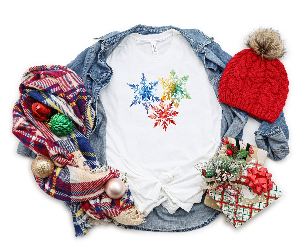 Colorful Watercolor Snowflakes T-Shirt white laid flat with denim jacket, plaid scarf, red beanie, ornaments and gifts