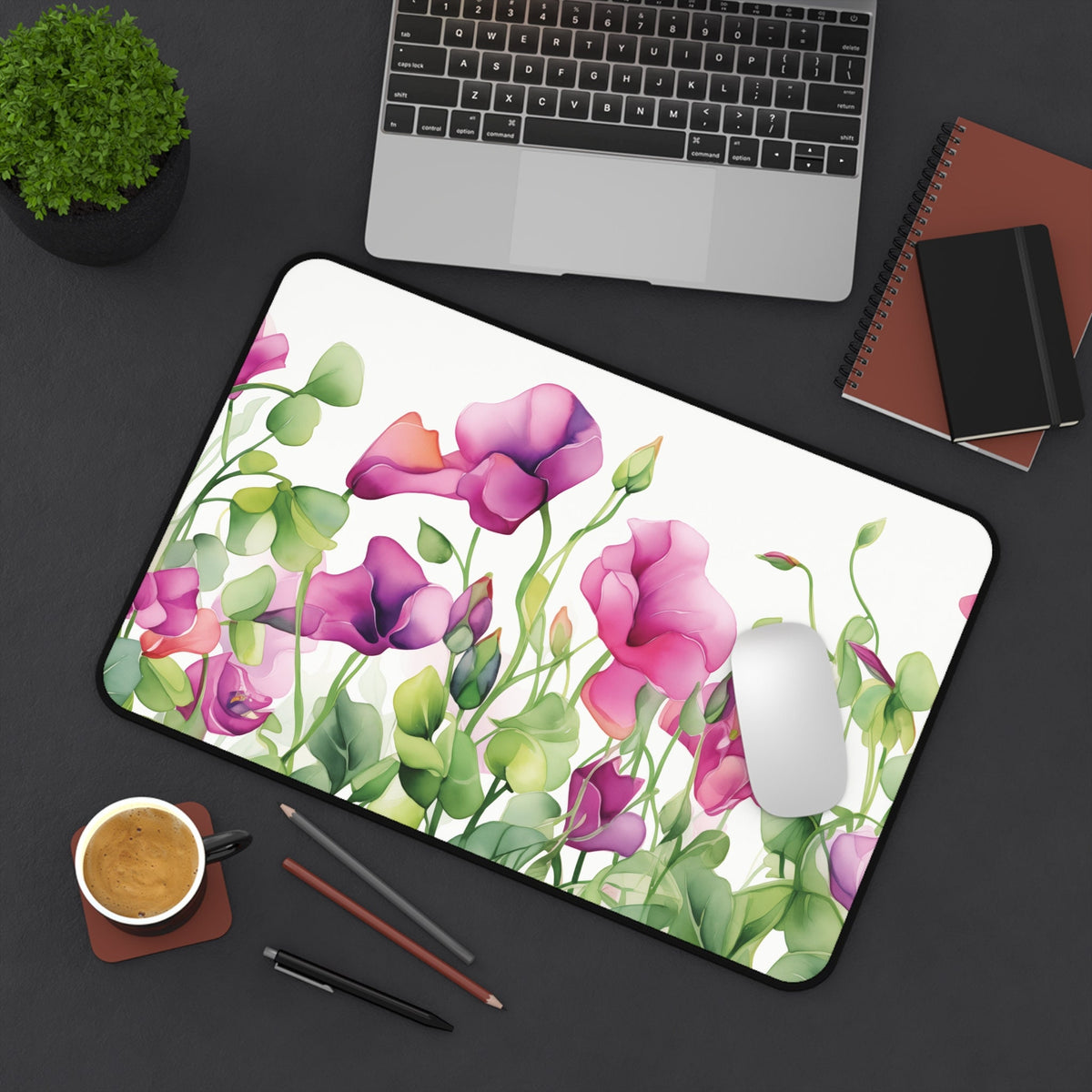Watercolor Sweet Pea Flowers Desk Mat, 12 × 18 inches, overhead on a dark desk with laptop, plant, coffee, pens and mouse.