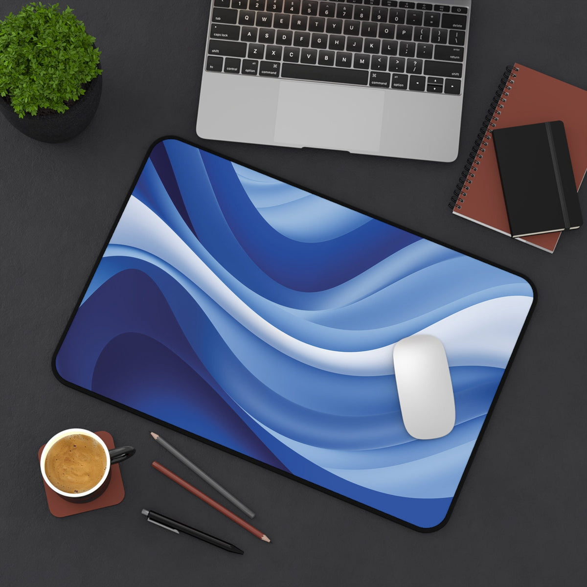 Abstract Desk Mat in blue waves on a dark desk with laptop, plant, coffee, pens and notebooks, 12 × 18 inches