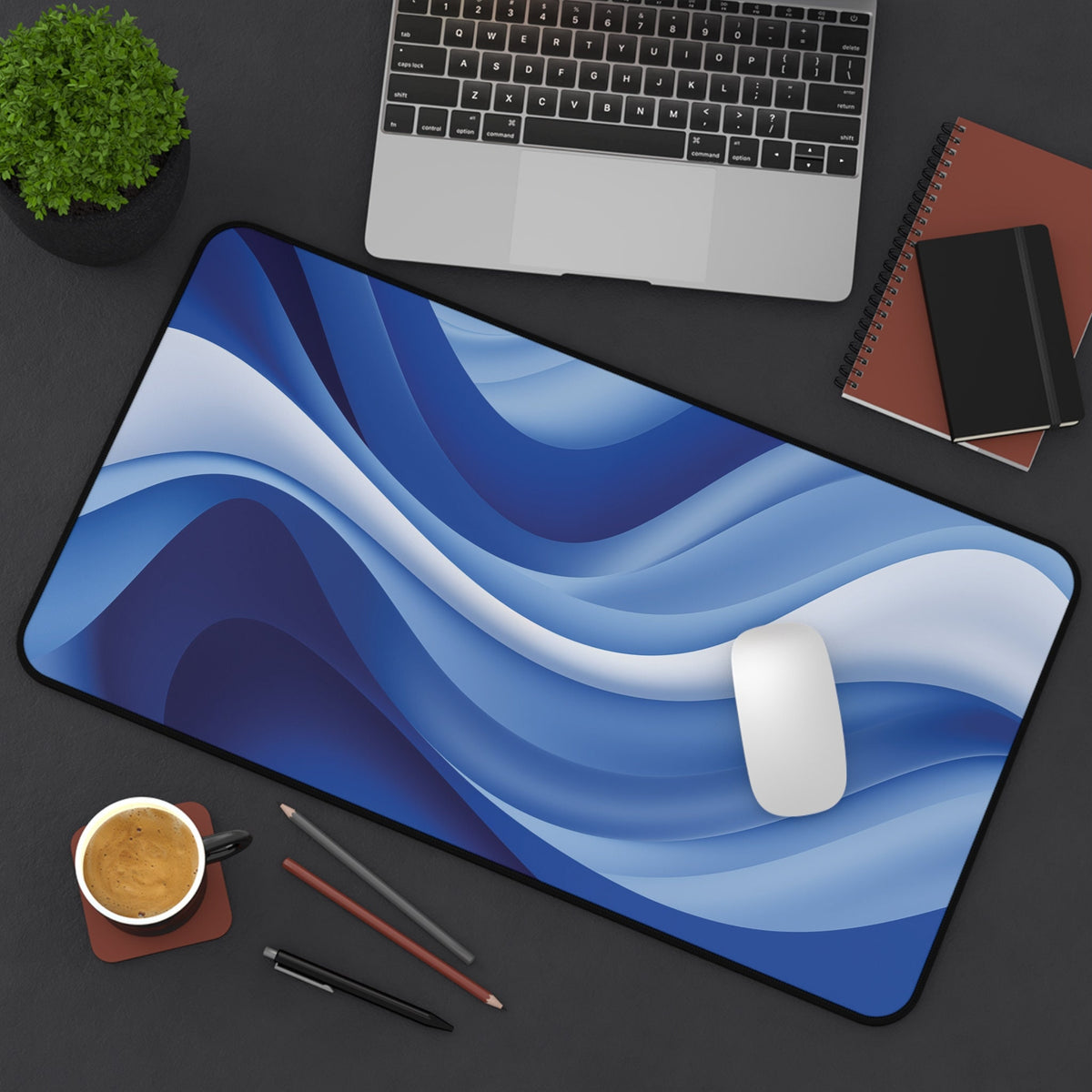 Abstract Desk Mat top-down on a desk with laptop, plant, notebooks, coffee cup and pens, 12 × 22 inches.
