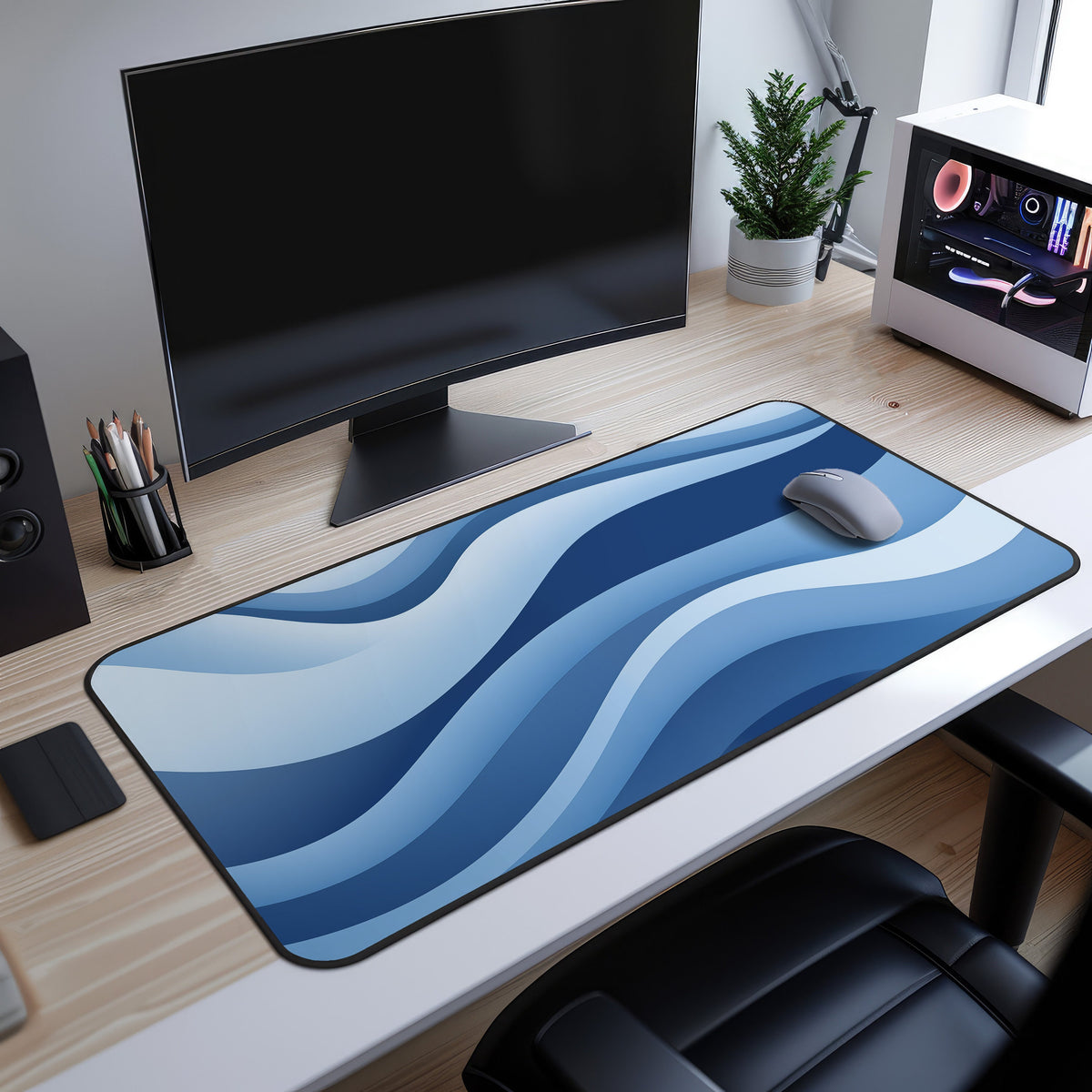 Abstract Desk Mat on a light wood desk beneath a curved black monitor, grey mouse on the blue wave pattern, PC and plant nearby.
