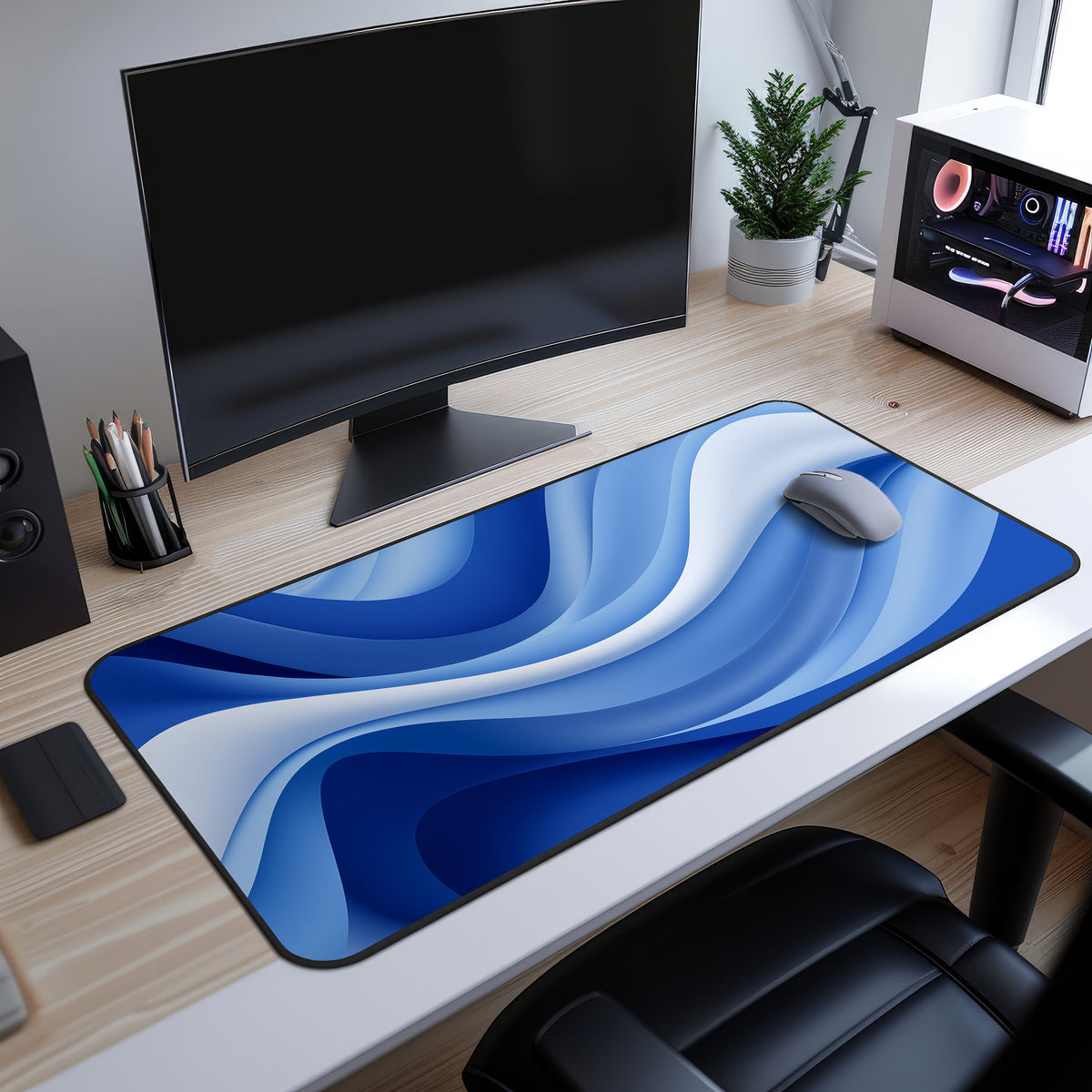 Abstract Blue Ocean Desk Mat on a wooden desk under a monitor with a mouse, potted plant and PC tower nearby.