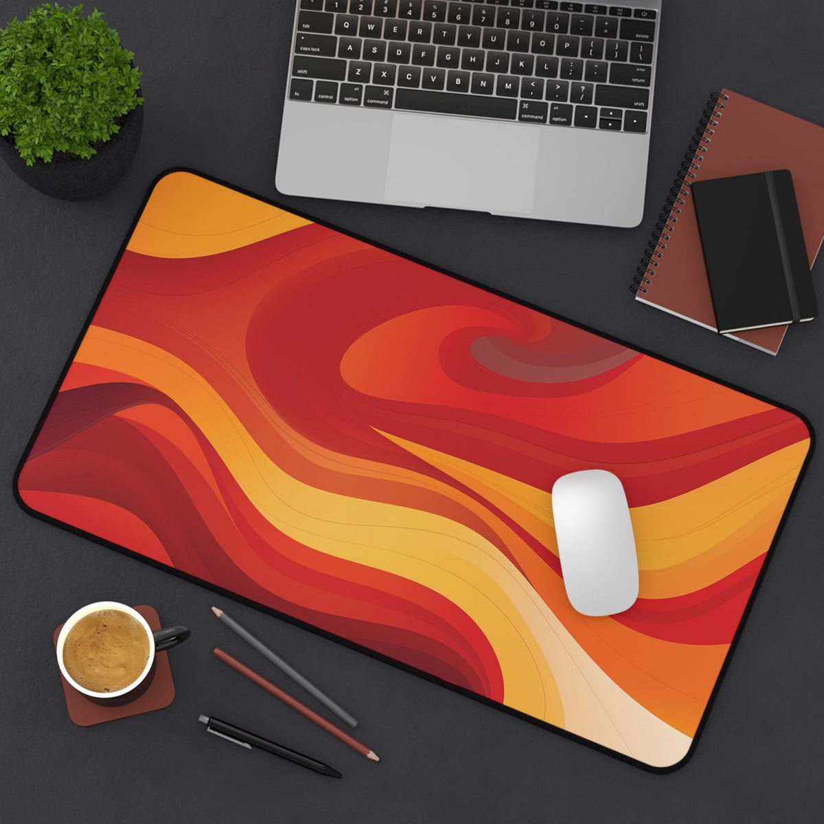 Abstract Lava Desk Mat in red-orange waves on a dark desk with laptop, mouse, coffee, and notebooks, 12 × 22 inches.