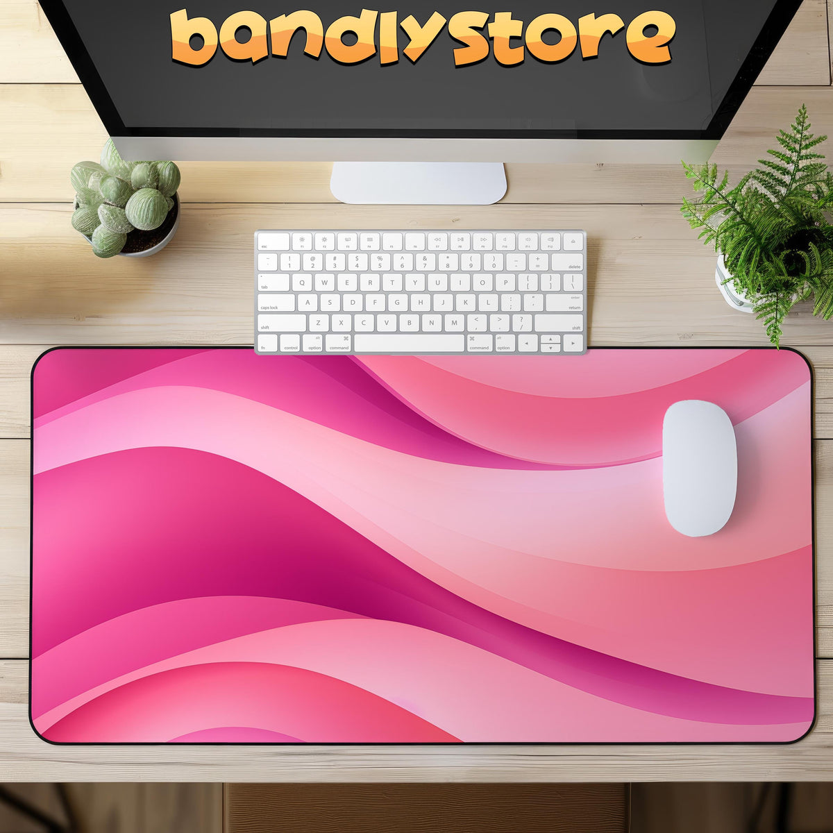 Abstract Desk Mat in pink waves on wooden desk with keyboard, mouse, monitor and plants, overhead view.