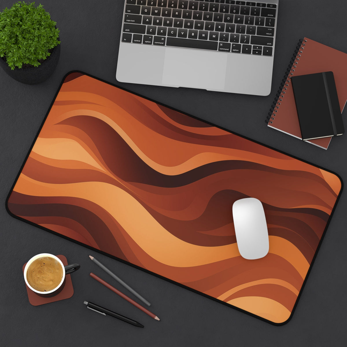 Abstract Wavy Desk Mat in warm orange tones on a dark desk with laptop, mouse, coffee and notebooks, 12 × 22 inches