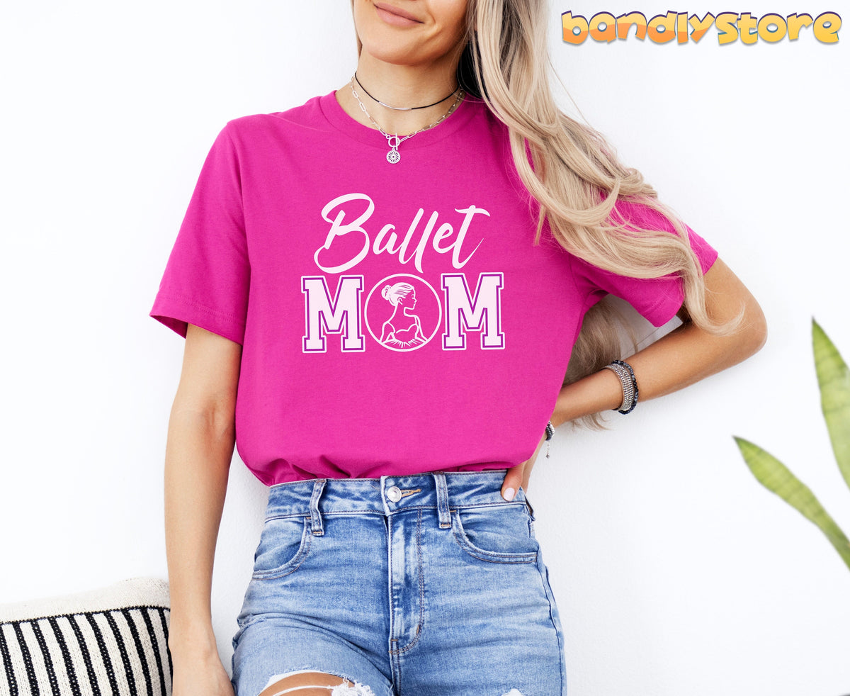 Ballet Mom T-Shirt in berry on a woman against a white wall beside a plant and striped pillow.