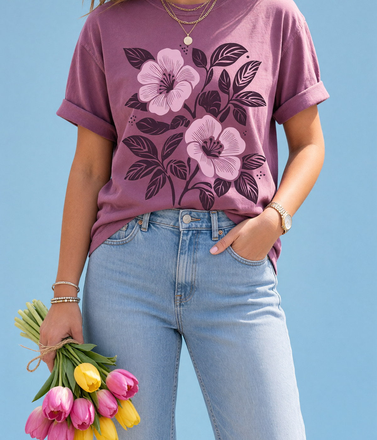 A woman in a printed floral t-shirt holding tulips, cropped at the shoulders, against a sky-blue backdrop