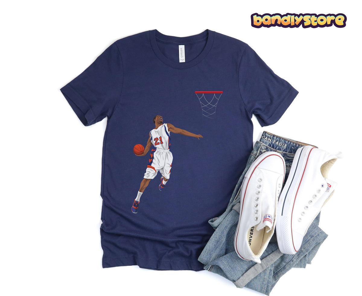 Basketball Slam Dunk T-Shirt in navy laid flat beside jeans and sneakers with dunking player graphic.