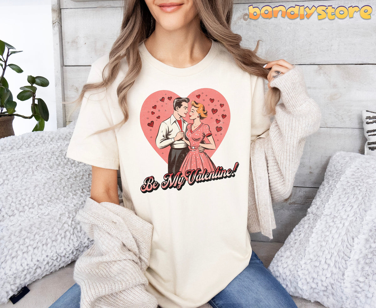 Be Mine Valentine T-Shirt in natural, front view on seated woman amid pillows, plant and wooden wall.