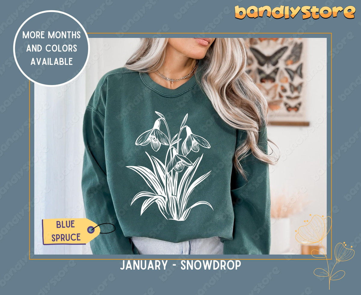 July Larkspur Birth Flower Sweatshirt in Blue Spruce on a model indoors beside a butterfly poster.