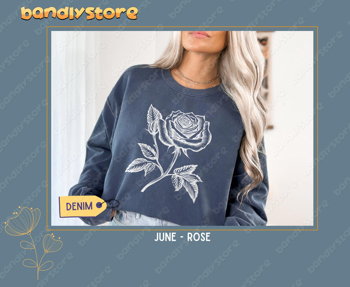July Larkspur Birth Flower Sweatshirt in denim on a model from the chest up with long blonde hair indoors by a curtain.
