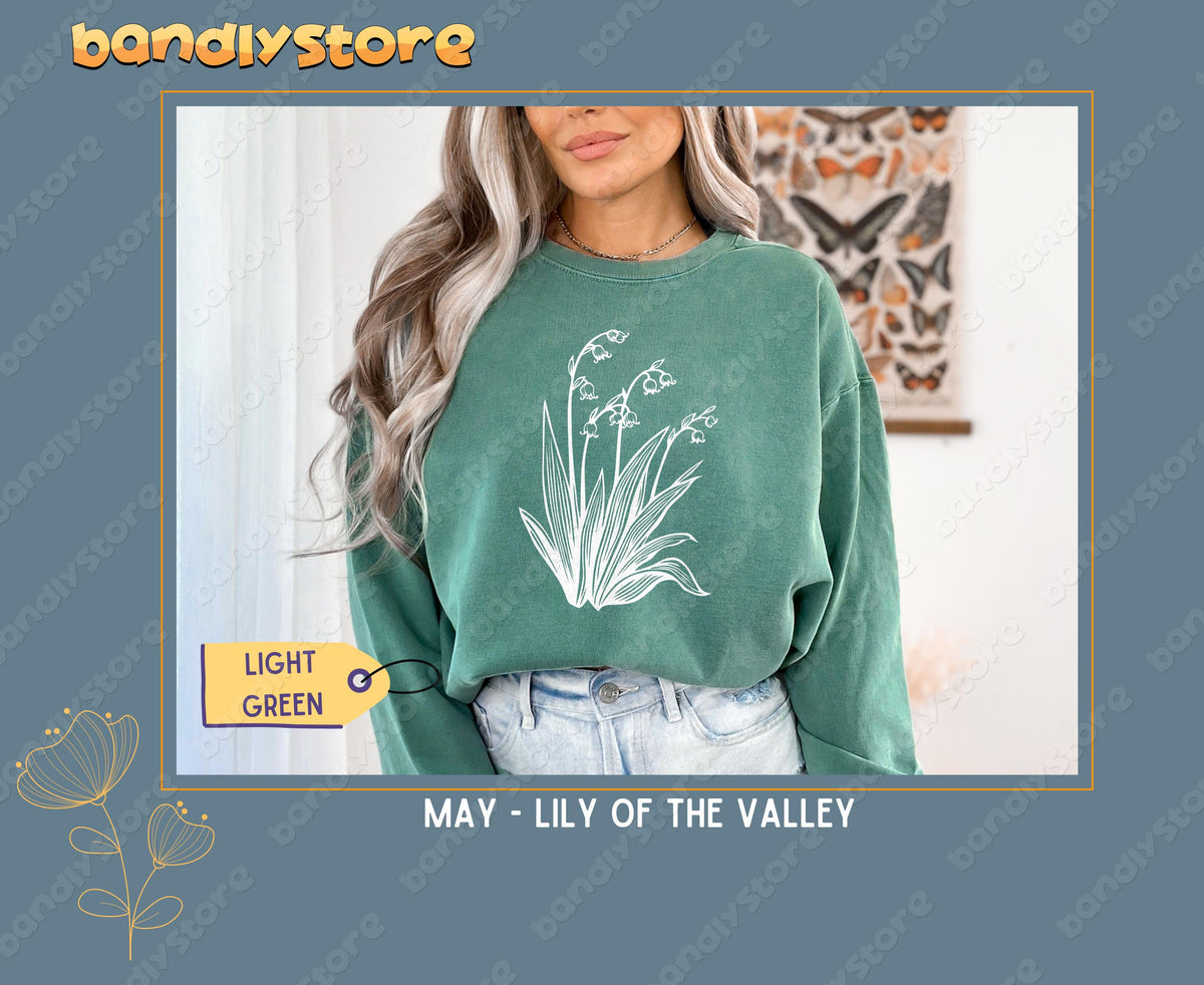 July Larkspur Birth Flower Sweatshirt in light green on a model facing forward indoors near a butterfly wall chart.