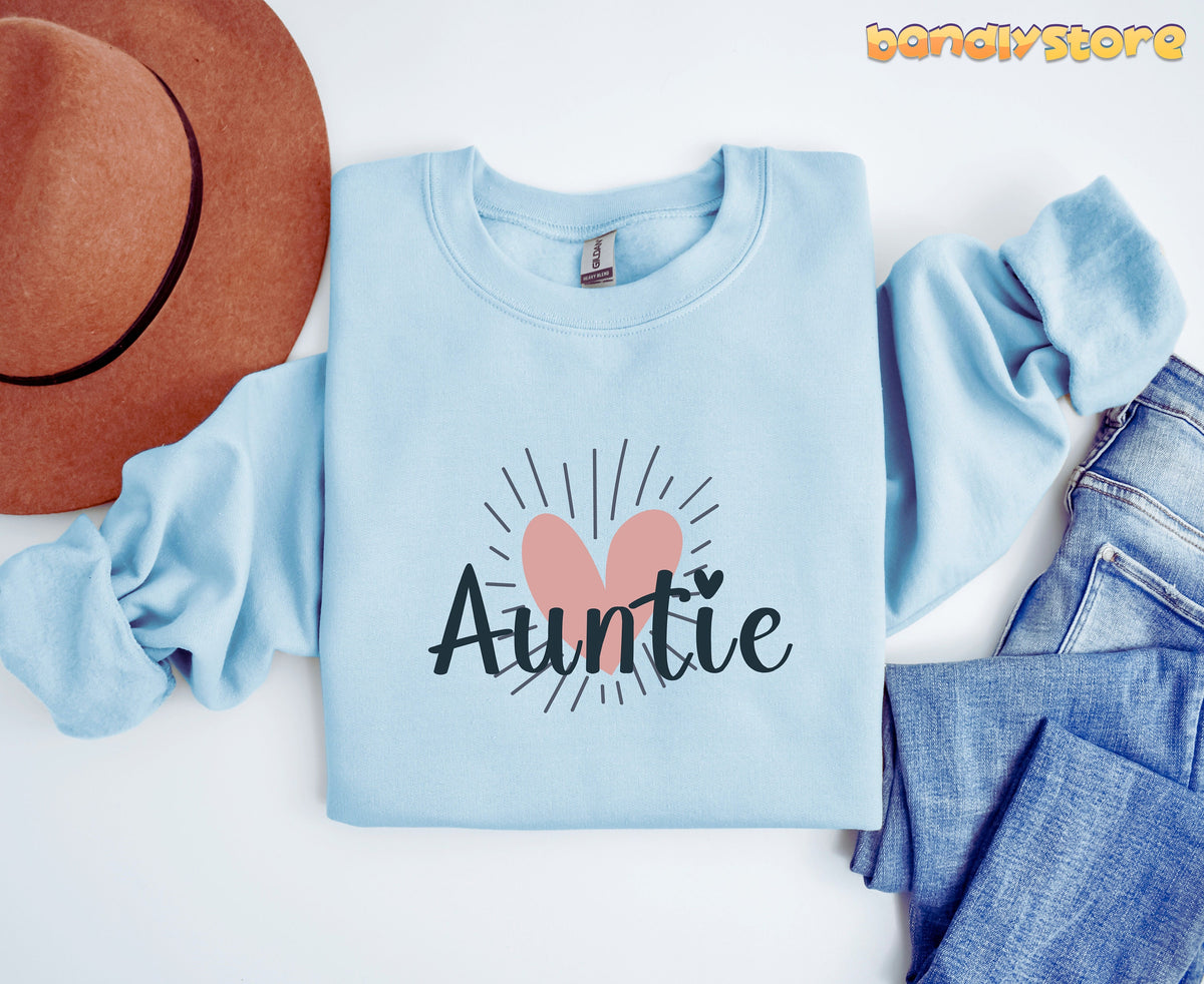 Boho Auntie Sweatshirt in light blue laid flat from above beside a brown hat and blue jeans.