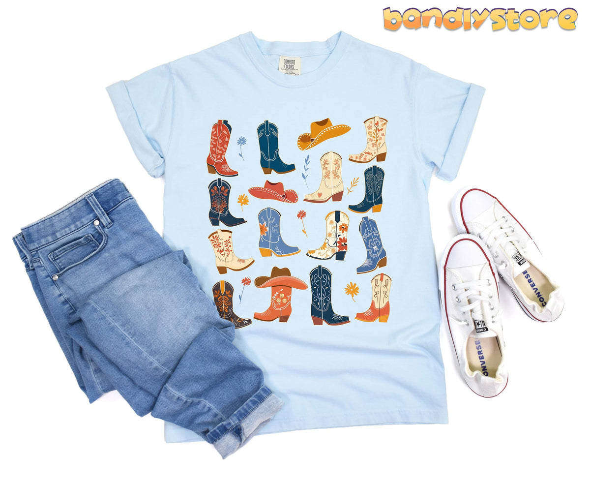 Boho Cowgirl Boots T-Shirt in Chambray, flat-laid with jeans left and white sneakers right.